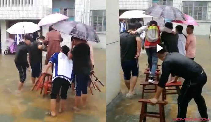 学生雨中帮老师垫脚